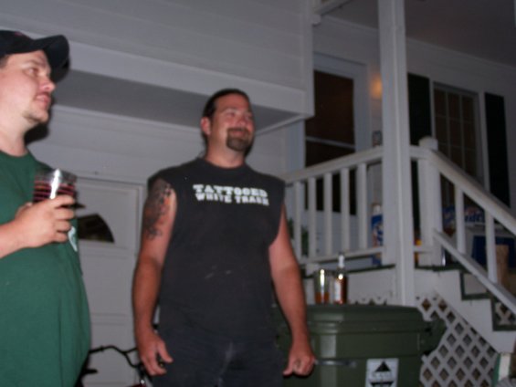 Man in black t-shirt with white text, standing on porch
