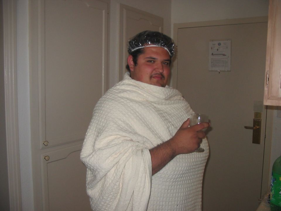 Man in bathrobe and shower cap holding a drink
