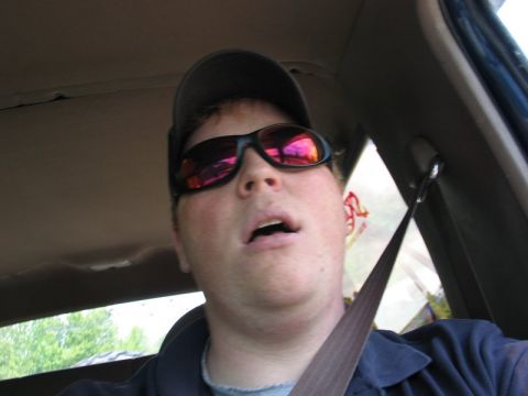 1995 Ford Bronco - A person is captured in a selfie from inside a vehicle, wearing sunglasses and a hat.