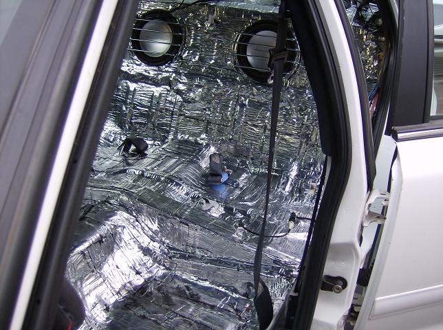 Sedan rear interior stripped to bare floor and covered in foil sound deadener with rear-deck speakers