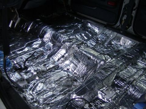 1999 Ford Crown Victoria - The interior floor of a vehicle is covered with sound deadening material, revealing exposed wiring.