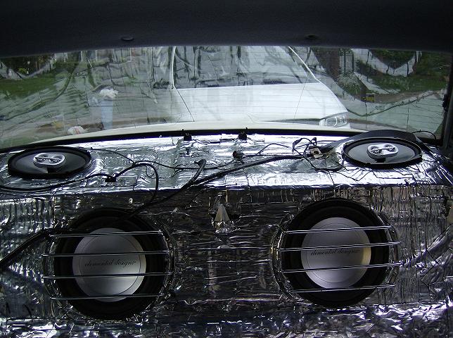 Car interior with sound deadening and two large subwoofers and two smaller speakers visible