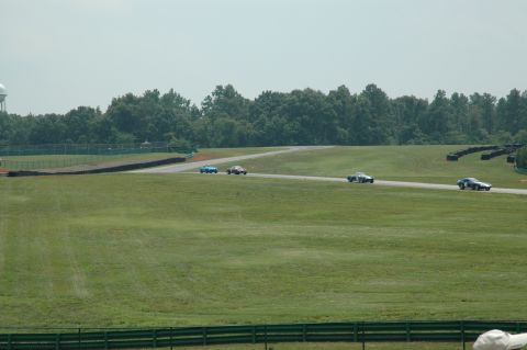 2000 Ford Mustang - Several vintage cars compete on a race track under a hazy sky.