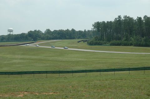 2000 Ford Mustang - Multiple vehicles compete on a race track, with a water tower visible in the distance.