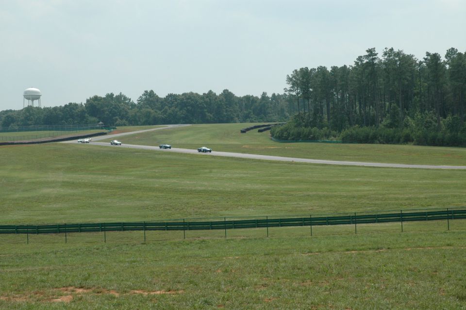 Four cars racing on a track with a water tower in the background