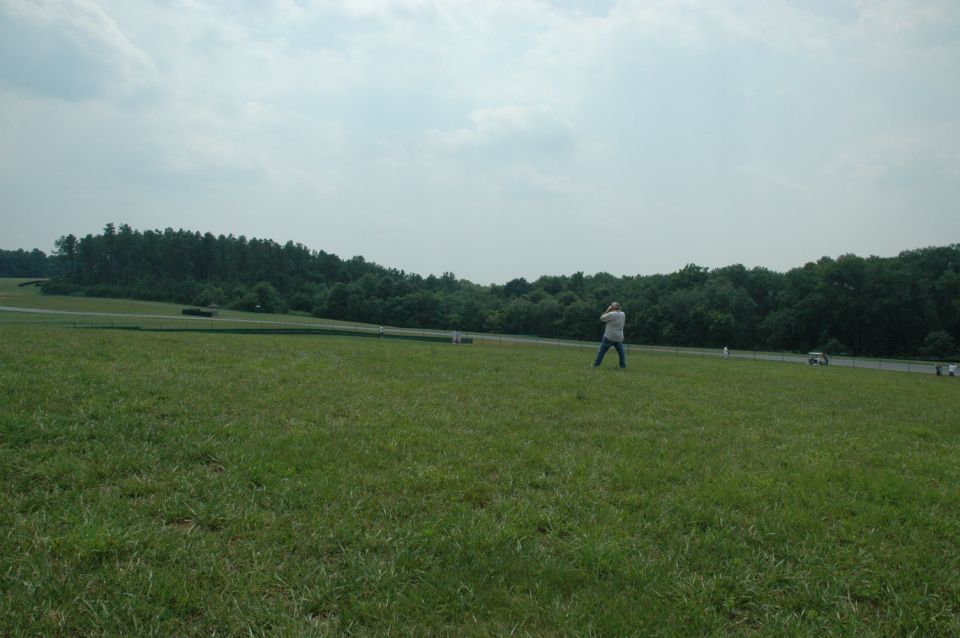 Person standing in a grassy field with trees in the background