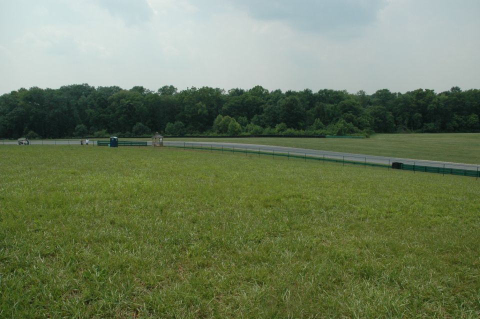 Two white cars on a track with a wooded background