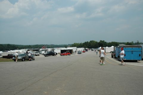 2000 Ford Mustang - A wide shot of a busy parking lot with many vehicles and people milling about.