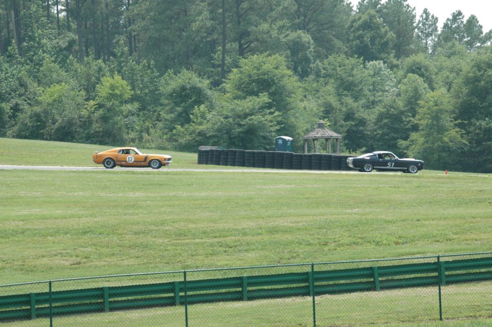 Orange 1969 Mustang with number 17 and black 1969 Mustang with number 51 on a race track