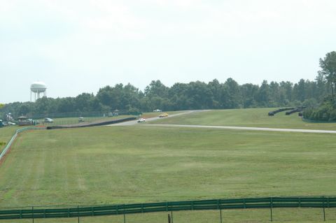 2000 Ford Mustang - A race track scene with multiple cars visible on the asphalt, under a hazy sky.