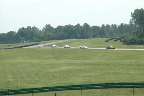 2000 Ford Mustang - Multiple vintage cars are seen on a race track during a sunny day.