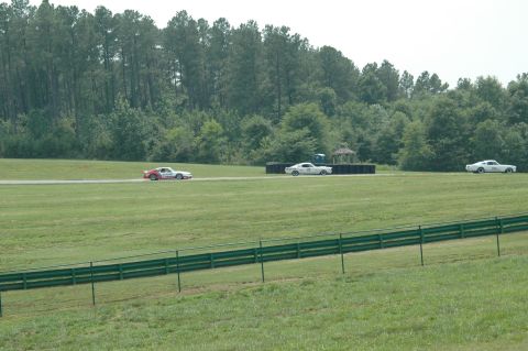 2000 Ford Mustang - Multiple cars are seen on a race track during a sunny day.