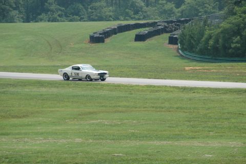 2000 Ford Mustang - A classic 1967 Ford Mustang competes on a race track with tire barriers in the background.