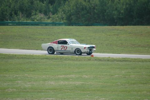 2000 Ford Mustang - A classic Ford Mustang race car with number 70 on its side navigates a turn on a sunny day.