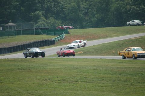 2000 Ford Mustang - Several vintage race cars compete on a sunny day at a track.
