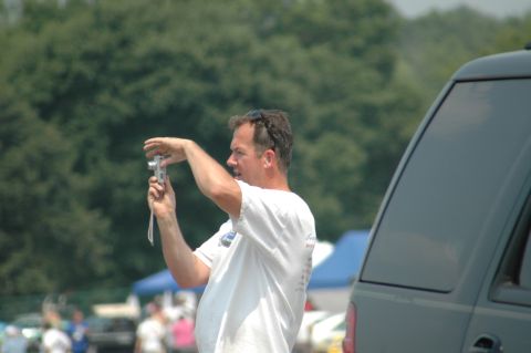 2000 Ford Mustang - A man is focused on taking a picture with his camera while standing outdoors near a dark-colored SUV.