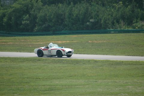 2000 Ford Mustang - A white convertible race car with red stripes and the number 11 is seen on a race track.