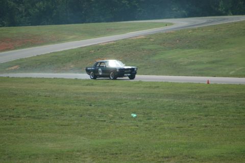 2000 Ford Mustang - A classic car navigates a turn on a sunny day at the racetrack.