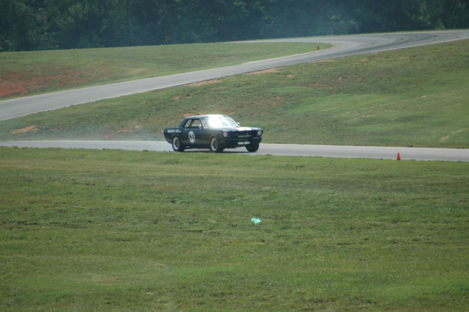 Black vintage race car with number 54 on the door driving on a track