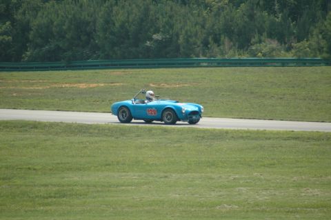 2000 Ford Mustang - A blue convertible race car with the number 120 is seen on a race track with grassy areas and trees in the background.