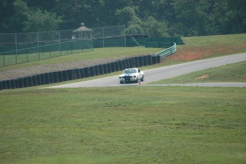 2000 Ford Mustang - White 1967 Ford Mustang with blue stripes driving on a racetrack.