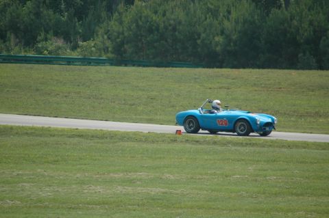2000 Ford Mustang - A blue convertible race car with the number 129 is seen on a race track with grassy surroundings.