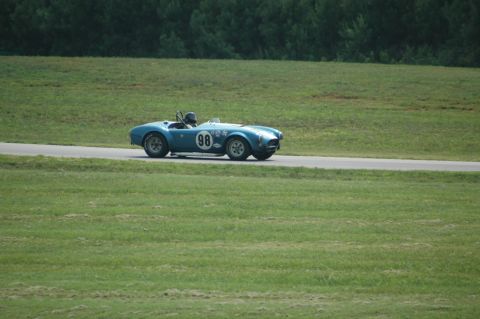 2000 Ford Mustang - A blue convertible race car with the number 98 is seen on a track surrounded by grassy fields.