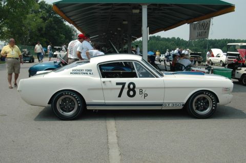 2000 Ford Mustang - A white 1965 Ford Mustang GT350 race car with blue stripes and the number 78 is parked at a track event.