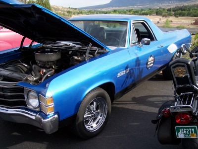 1972 Ford Ranchero - A blue pickup truck with its hood open is parked next to a motorcycle.