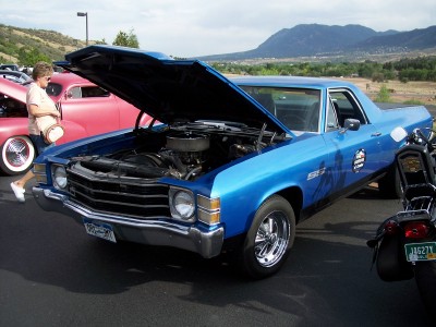 1972 Ford Ranchero - A blue 1972 Ford Ranchero is displayed with its hood open, revealing the engine, at an outdoor event with mountains visible.