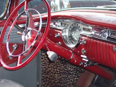 1972 Ford Ranchero - The interior of a classic car features a vibrant red dashboard and steering wheel, accented by a leopard print floor mat.
