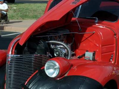 1972 Ford Ranchero - A red hot rod truck's engine is exposed with its hood open, revealing chrome components.