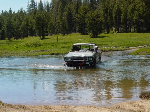 1986 Ford Bronco - A gray 1978 Ford Bronco navigates a river crossing surrounded by trees and a grassy field.