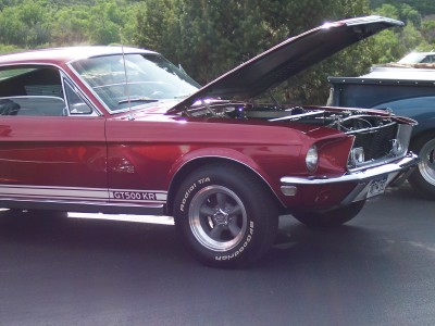 1972 Ford Ranchero - A red 1968 Shelby GT500 KR Mustang is shown with its hood up, parked outdoors next to another vehicle.