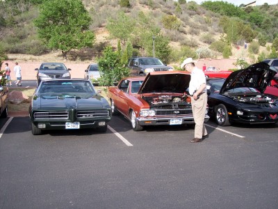 1972 Ford Ranchero - A green 1969 Pontiac Grand Prix is parked next to other vehicles at an outdoor event.