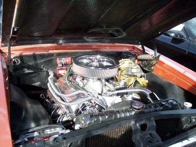 1972 Ford Ranchero - The engine bay of a copper-colored vehicle features a prominent chrome air cleaner and polished exhaust manifold.