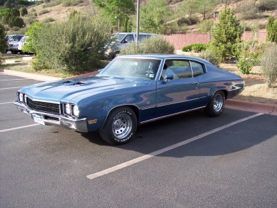 1972 Ford Ranchero - A blue coupe with distinctive hood scoops is parked in a lot, possibly at a car show.