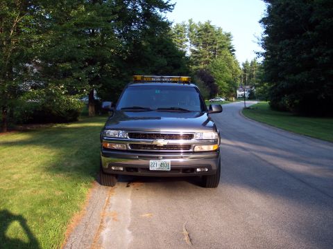 2002 Chevrolet Suburban - A dark gray Chevrolet SUV is parked on the side of a road in a suburban neighborhood.