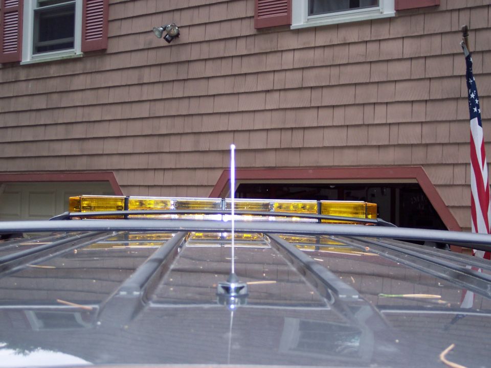Gray SUV roof with yellow light bar and antenna