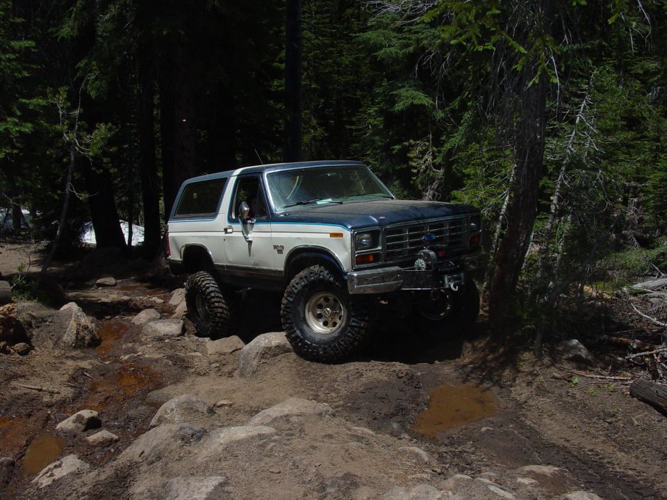 1986 Ford Bronco navigating a rocky trail in a forest