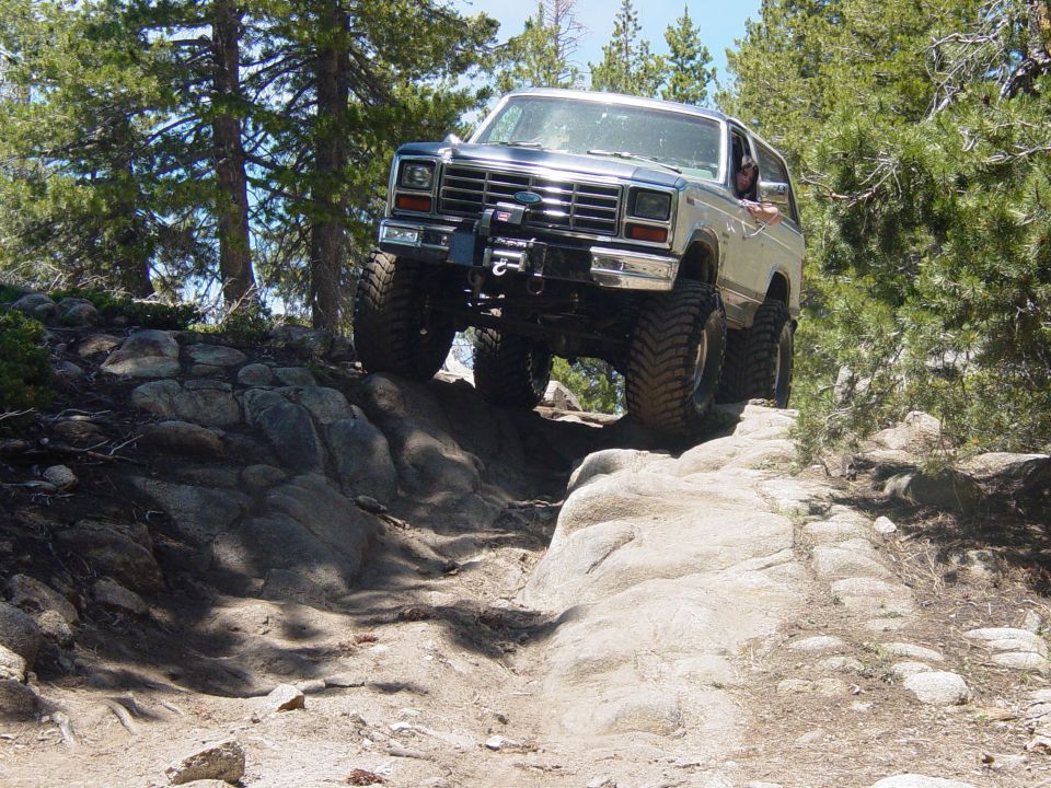 Silver Ford Bronco with large tires climbing a rocky trail