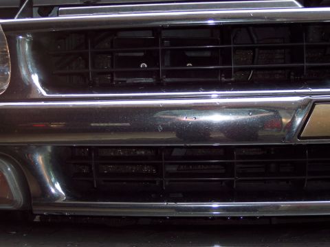 2002 Chevrolet Suburban - Close-up view of a vehicle's front grille and bumper, showing chrome accents and black grates.