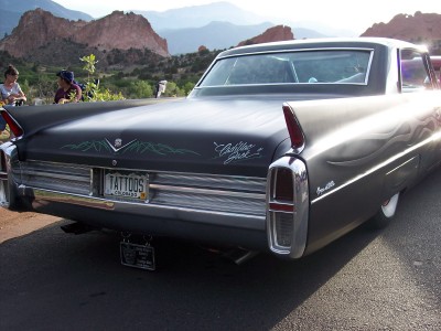 1972 Ford Ranchero - A custom 1960s Cadillac with flame pinstriping and a personalized license plate is parked with a scenic mountain backdrop.