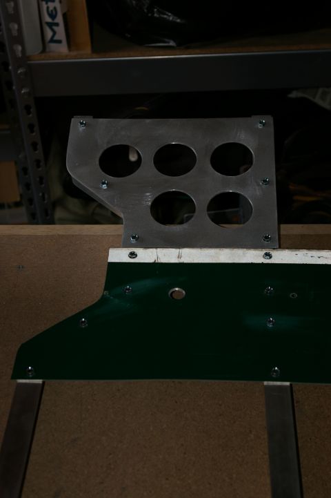 1986 Ford Bronco - A metal bracket with six circular openings is attached to a green panel.