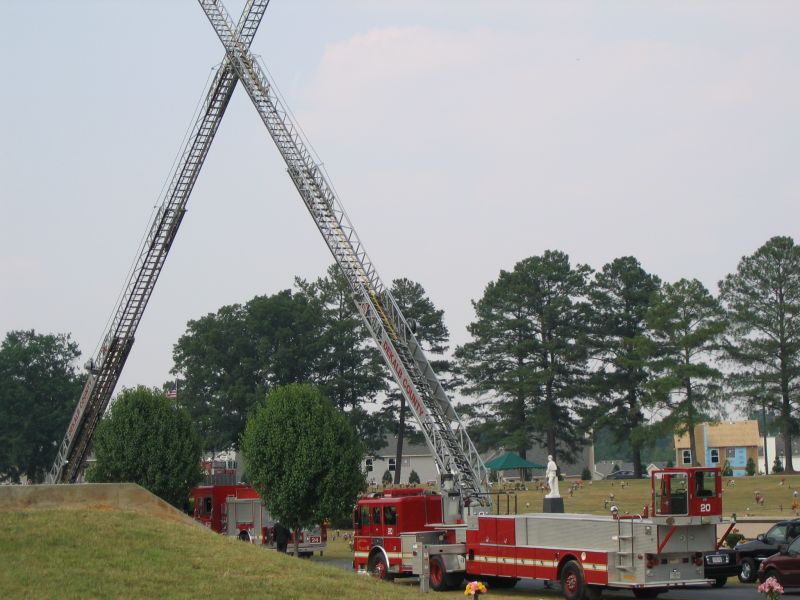 Fire trucks with ladders extended in a cemetery