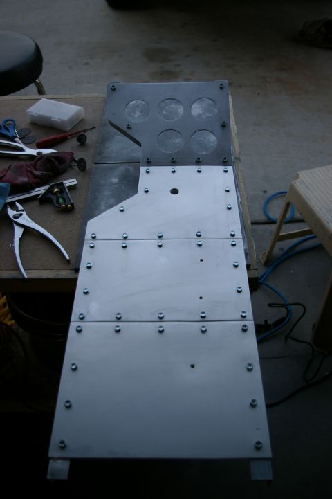 1986 Ford Bronco - Metal console assembly with six circular cutouts and many screws, possibly for electronics or storage.