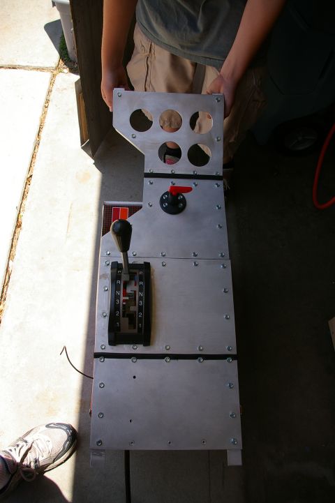 1986 Ford Bronco - A custom-built center console unit an automatic transmission shifter and a red toggle switch is held by two people.