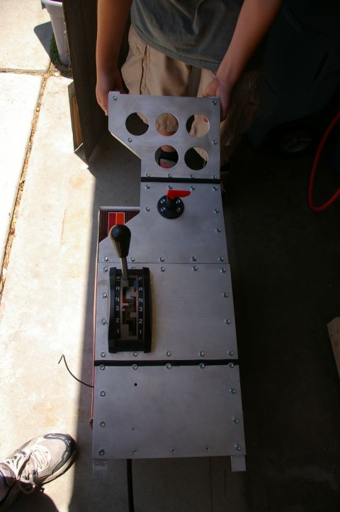 1986 Ford Bronco - A custom-made automotive shifter console is held by two people outdoors.