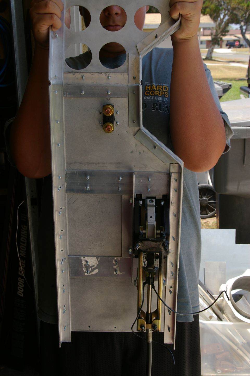 Metal bracket assembly with circular cutouts and mechanical linkage, held by a person