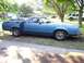1972 Ford Ranchero - This blue pickup truck is parked on a dirt road with trees in the background.